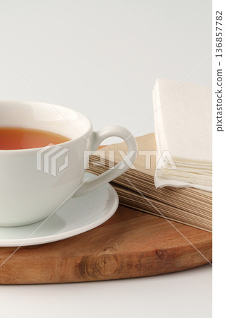 Hot tea in a white cup on a wooden board with napkins nearby in a simple setting Hot tea in a white cup on a wooden board with napkins nearby in a simple setting 136857782