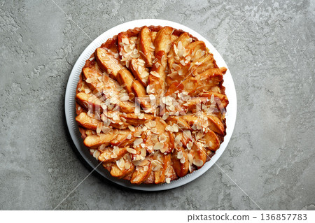 Freshly baked apple tart with almond slices on a white plate Freshly baked apple tart with almond slices on a white plate 136857783