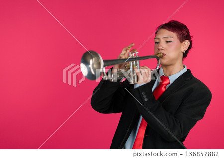 Musician playing trumpet against pink background 136857882