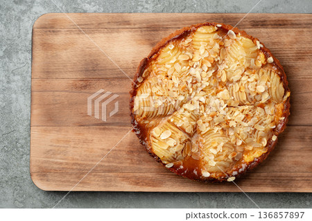 Pastry with sliced fruit and nuts on a wooden board in a kitchen setting Pastry with sliced fruit and nuts on a wooden board in a kitchen setting 136857897