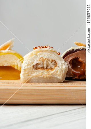Different types of dessert rolls on a wooden board in a kitchen setting 136857911