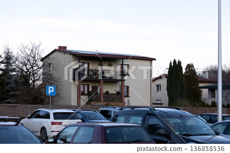 Residential building with balcony in a parking lot during late afternoon Residential building with balcony in a parking lot during late afternoon 136858536