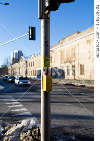 Traffic light signals pedestrians at a crosswalk in a city street 136858602