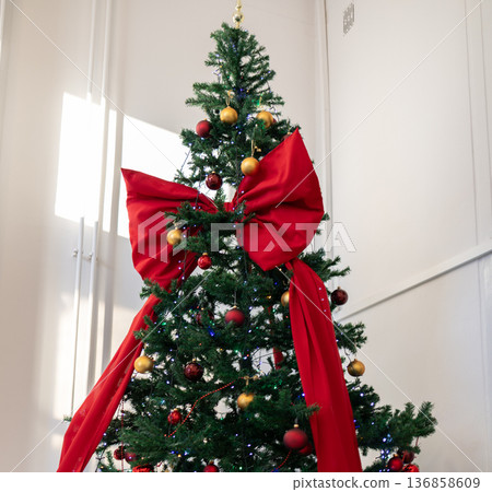 Christmas tree decorated with red bow and ornaments in bright room 136858609