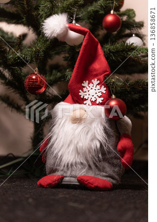 Gnome decoration by Christmas tree with red ornaments and a hat Gnome decoration by Christmas tree with red ornaments and a hat 136858671