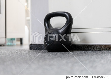 Kettlebell rests on the carpet next to a cabinet in a gym space Kettlebell rests on the carpet next to a cabinet in a gym space 136858693