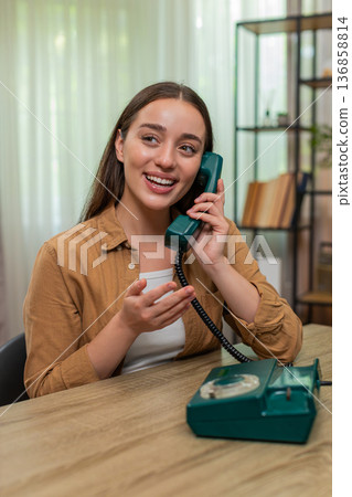 Young woman laughing on vintage wired telephone enjoying cheerful retro style conversation full fun Young woman laughing on vintage wired telephone enjoying cheerful retro style conversation full fun 136858814