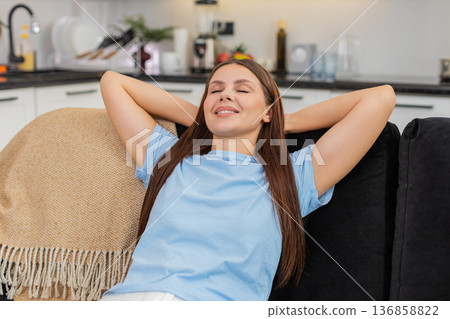 Young woman leans back smiles with hands behind head relaxed chill posture easy rest calm and happy 136858822