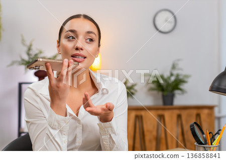 Young businesswoman records voice message states argument and listens to reply on smartphone speaker 136858841
