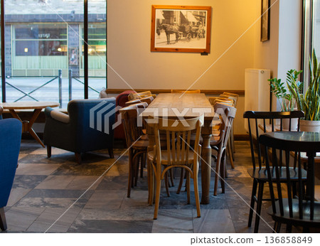Cozy cafe interior with wooden tables and chairs near a city street Cozy cafe interior with wooden tables and chairs near a city street 136858849