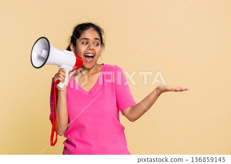Indian woman energetically speaking into megaphone, making announcement or calling with excitement Indian woman energetically speaking into megaphone, making announcement or calling with excitement 136859145