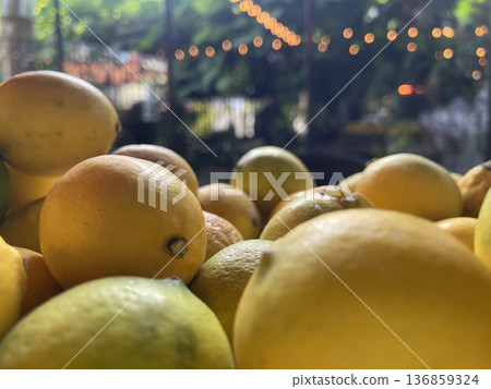 Lemons are placed on a tray in a dining space surrounded by plants.  136859324