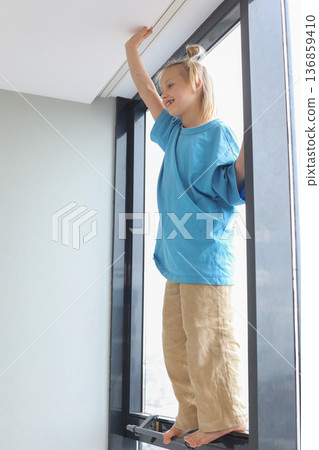 Smiling child standing high and touching the white ceiling with her hand at home. Smiling child standing high and touching the white ceiling with her hand at home. 136859410