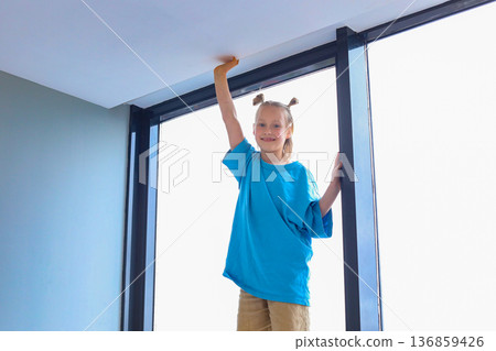 Funny little girl having fun on window indoor. Kid 6 years old portrait Funny little girl having fun on window indoor. Kid 6 years old portrait 136859426