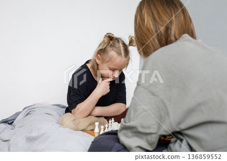 A brother and sister of junior school age play chess at home A brother and sister of junior school age play chess at home 136859552