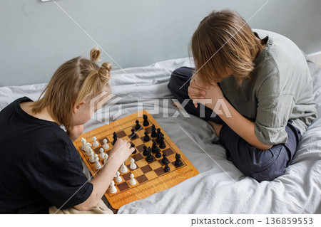 Cute kids, siblings or boy and girl together for learning games. Children playing chess Cute kids, siblings or boy and girl together for learning games. Children playing chess 136859553