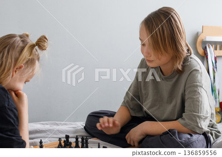 Happy brother and sister of junior school age play chess at home 136859556