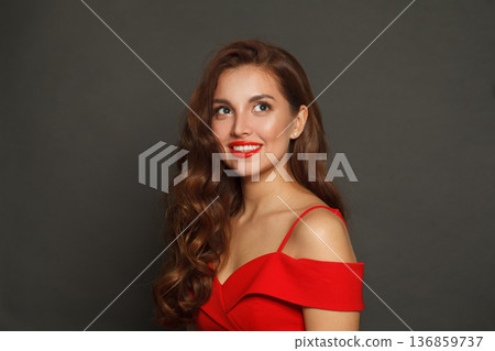 Cheerful fashion model woman with shiny skin, wavy hairstyle and red lips makeup on black background 136859737