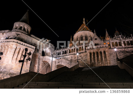 Fisherman's Bastion in Budapest illuminated at night. The historic structure features turrets and arches, surrounded by a quiet plaza. 136859868