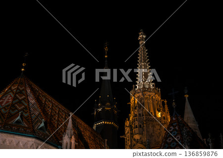 Fisherman's Bastion in Budapest illuminated at night. The historic structure features turrets and arches, surrounded by a quiet plaza. Fisherman's Bastion in Budapest illuminated at night. The historic structure features turrets and arches, surrounded by a quiet plaza. 136859876