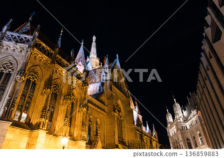 Fisherman's Bastion in Budapest illuminated at night. The historic structure features turrets and arches, surrounded by a quiet plaza. Fisherman's Bastion in Budapest illuminated at night. The historic structure features turrets and arches, surrounded by a quiet plaza. 136859883