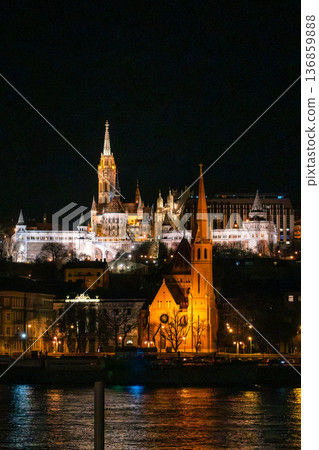 Fisherman's Bastion in Budapest illuminated at night. The historic structure features turrets and arches, surrounded by a quiet plaza. 136859888