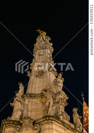 Night view of Fisherman Bastion and church in Budapest's castle district. Illuminated architecture, cobblestone streets, and historic buildings create a picturesque scene. Night view of Fisherman Bastion and church in Budapest's castle district. Illuminated architecture, cobblestone streets, and historic buildings create a picturesque scene. 136859911