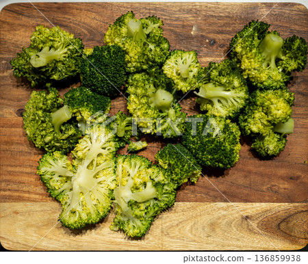 Fresh broccoli laid out on a wooden cutting board at kitchen counter 136859938