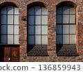 An old brick building with large arched windows and a wooden door 136859943