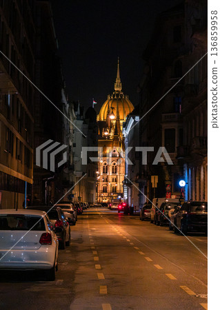 Budapest Parliament building illuminated at night. The architectural details are highlighted by warm lights. A clear sky enhances the scene. Budapest Parliament building illuminated at night. The architectural details are highlighted by warm lights. A clear sky enhances the scene. 136859958