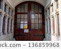 Large wooden door with glass panels in a stone building 136859968