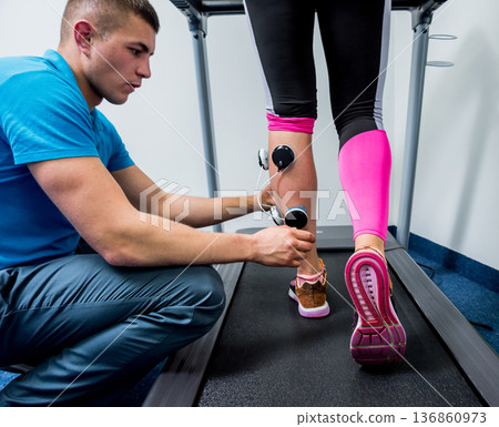 Physical therapist install electrostimulator on the muscles of the legs. Physical therapist install electrostimulator on the muscles of the legs. 136860973