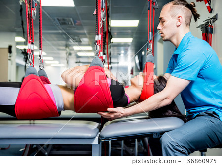 Physiotherapy. Suspension training therapy. Young woman doing fitness traction Physiotherapy. Suspension training therapy. Young woman doing fitness traction 136860975