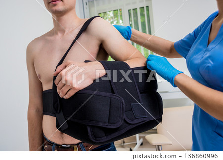 Nurse putting a sling on patients arm that is broken. Injury Nurse putting a sling on patients arm that is broken. Injury 136860996