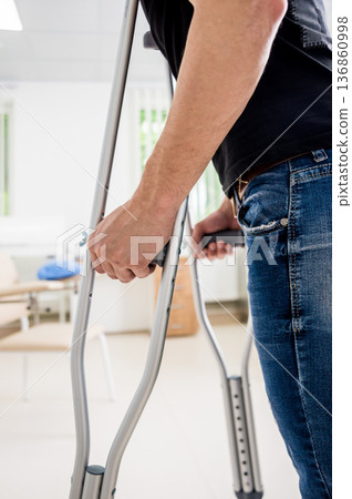 Injured man trying to walk on crutches in the hospital. Injured man trying to walk on crutches in the hospital. 136860998