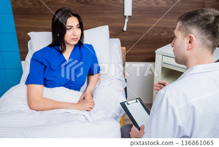 Traumatologist talking with young female patient in modern hospital Traumatologist talking with young female patient in modern hospital 136861065