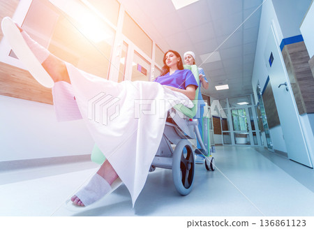 Nurse moves mobile medical chair with patient at hospital. Medical equipment. 136861123