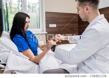 Traumatologist examining patient hands in modern hospital 136861136
