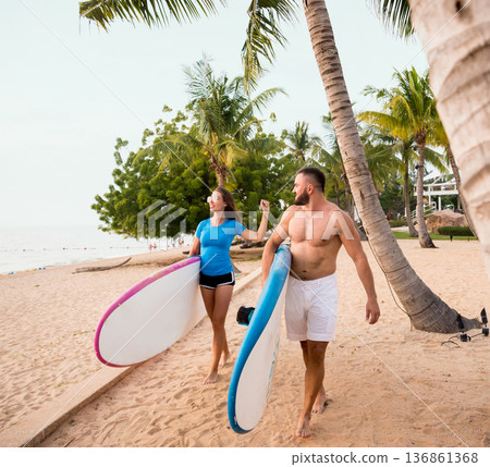 Two young surfers with boards on the beach Two young surfers with boards on the beach 136861368