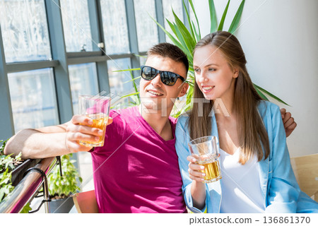 Cheerful couple in the pub. Drinking beer, talking, having fun. Cheerful couple in the pub. Drinking beer, talking, having fun. 136861370
