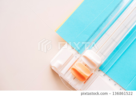 Paper cutter corner with blue cardstock and orange slider, minimal paper crafting background Paper cutter corner with blue cardstock and orange slider, minimal paper crafting background 136861522