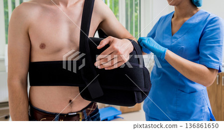 Nurse putting a sling on patients arm that is broken. Injury Nurse putting a sling on patients arm that is broken. Injury 136861650