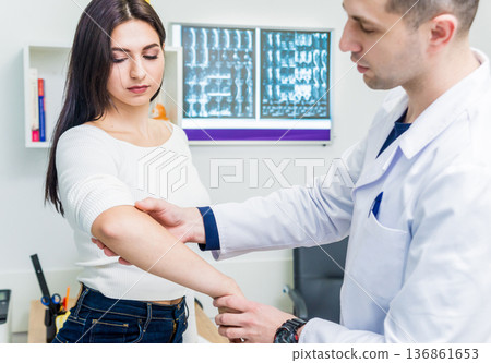 Traumatologist examining patient hands in modern hospital 136861653