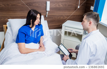 Traumatologist talking with young female patient in modern hospital Traumatologist talking with young female patient in modern hospital 136861691