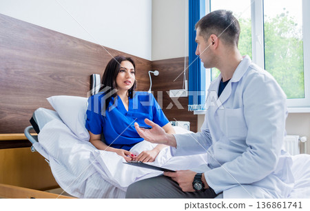 Traumatologist talking with young female patient in modern hospital Traumatologist talking with young female patient in modern hospital 136861741