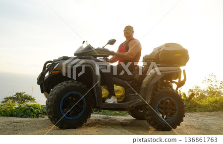 A man engages in extreme ATV riding on mountains in the evening A man engages in extreme ATV riding on mountains in the evening 136861763