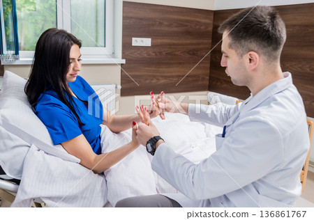Traumatologist examining patient hands in modern hospital Traumatologist examining patient hands in modern hospital 136861767