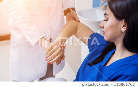 Traumatologist examining patient hands in modern hospital Traumatologist examining patient hands in modern hospital 136861768