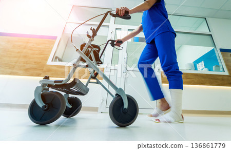 Patient on rollator with hand brakes moving in hospital Patient on rollator with hand brakes moving in hospital 136861779