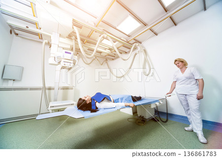 Radiologist and patient in a x-ray room. Classic ceiling-mounted x-ray system. Radiologist and patient in a x-ray room. Classic ceiling-mounted x-ray system. 136861783